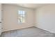 A bright bedroom features neutral paint, a window for natural light, and plush gray carpet at 1703 Wooten Way, Bessemer City, NC 28016