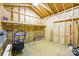 Interior view of an unfinished shed with a lawn mower, shovel, shelving, and sheets of plywood at 17219 Grand Central Way, Cornelius, NC 28031