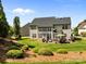 Back exterior of home with a grassy yard, patio area and an umbrella at 1900 Birchbrook Ct, Harrisburg, NC 28075