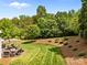 This is a lush back yard with manicured landscaping, a patio, and a wooded view at 1900 Birchbrook Ct, Harrisburg, NC 28075