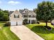 Charming two-story home boasts a lush green lawn, mature trees, and a convenient two-car garage at 1900 Birchbrook Ct, Harrisburg, NC 28075