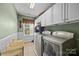 Well-lit laundry room with modern washer, dryer, white cabinetry, and window with natural light at 1900 Birchbrook Ct, Harrisburg, NC 28075
