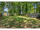 Fenced backyard with a lush lawn, tall trees, hot tub, and storage shed, offering a private and serene outdoor space at 2933 Hilliard Dr, Charlotte, NC 28205