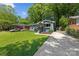 Quaint single-story home with a long driveway and lush green lawn, surrounded by mature trees and landscaping at 2933 Hilliard Dr, Charlotte, NC 28205