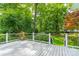 Back deck with a view of the landscaped yard with lush trees and a small garden area, and white deck railing at 532 Courtney Ln, Matthews, NC 28105