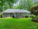 Exterior of home with a spacious, well-manicured backyard and mature landscaping; some parts of the brick are painted gray at 532 Courtney Ln, Matthews, NC 28105