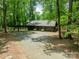 Three-car detached garage surrounded by lush trees and gravel, a place to store your vehicles and gardening equipment at 532 Courtney Ln, Matthews, NC 28105