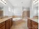 Bright bathroom featuring a soaking tub, glass shower, and dual sink vanity at 581 Harrison Nw Dr, Concord, NC 28027