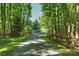 A tree-lined driveway bordered by a wooden fence offering a scenic approach to the property at 6108 Phyliss Ln, Mint Hill, NC 28227