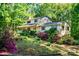 Charming two-story home featuring a covered porch and surrounded by lush landscaping with colorful flowers and mature trees at 6766 Little Mountain Rd, Sherrills Ford, NC 28673