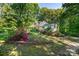 Charming home exterior with a covered front porch surrounded by lush greenery and flowering plants at 6766 Little Mountain Rd, Sherrills Ford, NC 28673