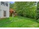 A view of a backyard featuring a wooden playset, lush greenery, and a well-maintained lawn at 7049 Sedgebrook W Dr, Stanley, NC 28164