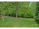Backyard view featuring an extended green lawn, a tree line, and wooded area at the rear of the property at 7049 Sedgebrook W Dr, Stanley, NC 28164