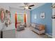 Cozy bedroom with a blue accent wall, comfortable seating, and a natural wood crib by a window at 7049 Sedgebrook W Dr, Stanley, NC 28164