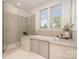 A modern bathroom featuring glass shower, soaking tub, and natural light from the large window at 710 Morgan Park Dr, Charlotte, NC 28204
