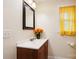 Cozy bathroom with a wood vanity, framed mirror, and a window covered by a sunny yellow curtain at 712 Grace Ave, Kannapolis, NC 28083