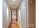 Hallway featuring hardwood floors and white doors, leading to a sunlit area with brick walls and artwork at 714 Larkhall Ln, Charlotte, NC 28211