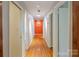 Long hallway with hardwood floors, white walls, and striking orange accent wall at the end at 714 Larkhall Ln, Charlotte, NC 28211