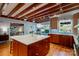 Open kitchen with island, wood cabinets, and breakfast bar adjacent to the living room with exposed beam ceiling at 714 Larkhall Ln, Charlotte, NC 28211