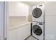 Functional laundry room with stacked washer and dryer, storage cabinets, and ample counter space at 714 Larkhall Ln, Charlotte, NC 28211
