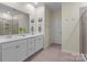 Bright bathroom featuring double sink vanity, large mirror, and glass-enclosed shower at 7620 Porrera St, Charlotte, NC 28214