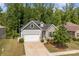 Inviting home featuring a stone and gray facade, a spacious driveway, and a manicured lawn with mature trees at 7620 Porrera St, Charlotte, NC 28214
