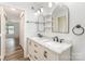 Bathroom with a double sink vanity, dark hardware, and modern light fixtures that leads to another room at 7718 Petrea Ln, Charlotte, NC 28227