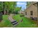 Landscaped backyard featuring a stone walkway leading to a firepit seating area, surrounded by lush greenery at 7730 Burning Ridge Dr, Stanley, NC 28164