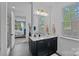 Chic bathroom with a dark vanity, white countertop, gold fixtures, large mirror, and view to main bedroom at 7730 Burning Ridge Dr, Stanley, NC 28164