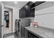 Modern laundry room with a gray washer and dryer, granite countertop, black cabinets, and walk-in closet at 7730 Burning Ridge Dr, Stanley, NC 28164