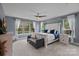 Spacious main bedroom featuring a decorative ceiling fan, bench seat and bright windows with backyard views at 7730 Burning Ridge Dr, Stanley, NC 28164
