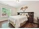 Comfortable bedroom showcasing hardwood floors, a decorative headboard, and natural light from a window at 7923 Shiny Meadow Ln, Charlotte, NC 28215