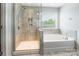 Bright bathroom featuring a tiled shower with glass door, soaking tub, and window at 9109 Loch Glen Way, Charlotte, NC 28278