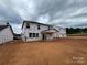 New construction featuring Tyvek home wrap, a covered porch, and a spacious backyard under a cloudy sky at 918 Windy Oak Ct, Indian Trail, NC 28079