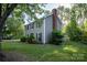View of the home from the left, featuring a brick chimney and lush green trees at 9801 Kent Village Dr, Charlotte, NC 28269