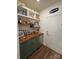 Stylish bar area with green cabinets, a mini fridge, wood shelves with liquor and glassware, and a nearby entry door at 104 Trellis Ln, Troutman, NC 28166