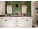 Bathroom showcases dual sinks, framed mirrors, accent wall, white cabinets, and a glass-enclosed shower for a spa-like retreat at 104 Trellis Ln, Troutman, NC 28166