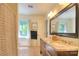 Bright bathroom featuring a double sink vanity with granite countertops, framed mirror, and window view at 10501 Stonemede Ln, Matthews, NC 28105