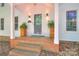 Covered front porch with brick steps, decorative plants, and a charming exterior at 10501 Stonemede Ln, Matthews, NC 28105