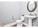 Powder room with pedestal sink, round mirror, and hardwood floors at 162 Kenway Loop, Mooresville, NC 28117