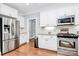 Well-lit kitchen with stainless appliances, white cabinets, granite countertops, and hardwood floors at 162 Kenway Loop, Mooresville, NC 28117