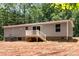 Back of house with stairs leading to a deck, gray siding, surrounded by wooded area and some yard space at 1785 Doe Ct, Iron Station, NC 28080