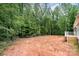 Large, cleared backyard with lush green trees offering privacy and a small wooden deck for outdoor enjoyment at 1785 Doe Ct, Iron Station, NC 28080