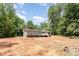 Rear exterior view of home, featuring a small deck and partially cleared land at 1785 Doe Ct, Iron Station, NC 28080