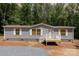 Charming single-story home with gray siding, white trim, and a small front porch nestled among lush green trees at 1785 Doe Ct, Iron Station, NC 28080