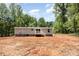 A backyard view of a charming single-story home featuring a cozy back porch and surrounded by lush trees at 1785 Doe Ct, Iron Station, NC 28080