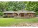 Backyard view of brick home featuring a covered porch and lush green lawn at 1874 Sunny Ln, Lancaster, SC 29720