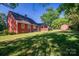 Backyard featuring a red home, brick patio, green grass, and a red shed at 2240 Armstrong Park Dr, Gastonia, NC 28054