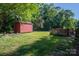 Red shed sits nestled in the lush, green backyard, adjacent to a charming brick patio at 2240 Armstrong Park Dr, Gastonia, NC 28054