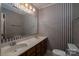 Bathroom with double sink vanity, mirror, and blue striped wallpaper at 2240 Armstrong Park Dr, Gastonia, NC 28054
